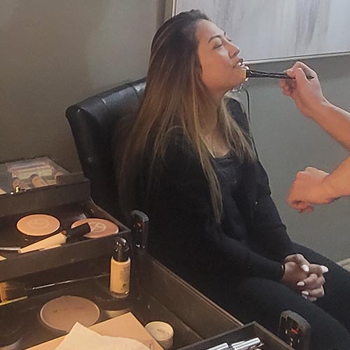 a woman in black attire getting her makeup done
